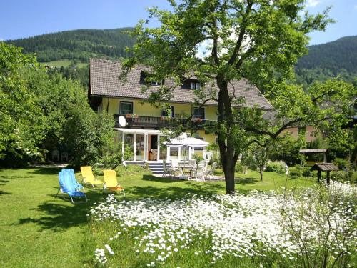 a house with chairs and flowers in the yard at Charming Apartment in Feld am See 100 m from Lake in Feld am See