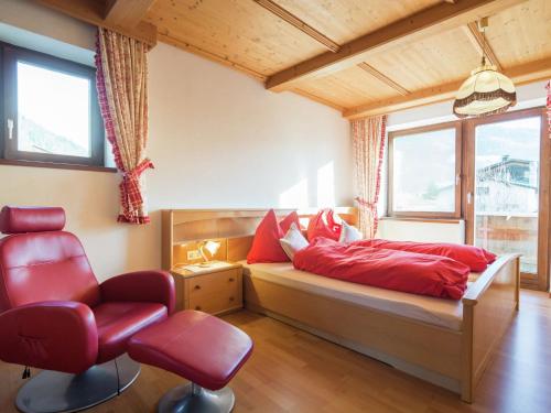 キルヒドルフ・イン・チロルにあるInviting Chalet in Kirchdorf in Tirol near City Centreのベッドルーム1室(赤い枕と椅子付きのベッド1台付)