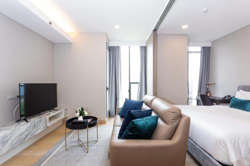 a bedroom with a bed and a couch and a tv at Wyndham Bangkok Queen Convention Centre in Bangkok