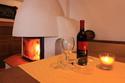 a bottle of wine and two glasses on a table with a fireplace at Tonis Ferienheim in Sölden
