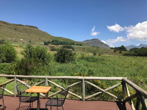 a wooden deck with chairs and a table on it at Sani Lodge & Cottages in Sani Pass
