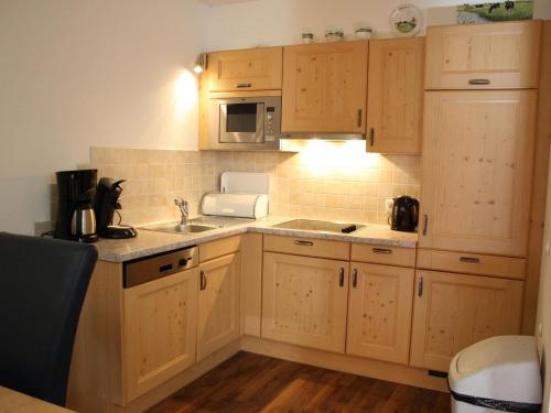Kuchnia z drewnianymi szafkami, zlewem i kuchenką mikrofalową w obiekcie Apartment in Kaprun near ski lift w Kaprunie