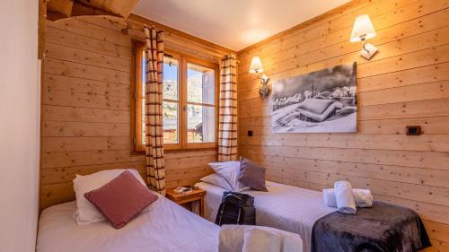2 łóżka w pokoju z drewnianymi ścianami w obiekcie Madame Vacances Les Chalets de l'Altiport w LʼAlpe-dʼHuez