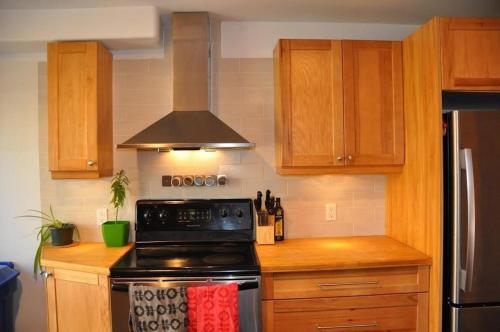 a kitchen with wooden cabinets and a stove top oven at Le Tierra del Fuego by HomeInMontreal in Montréal