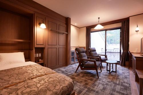 a hotel room with a bed and a desk and chairs at Le Chien Kyukaruizawa in Karuizawa