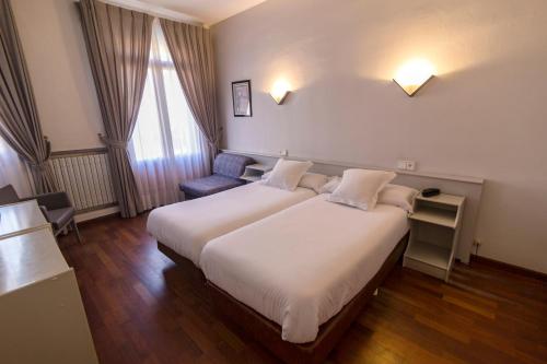 グラウスにあるHospedium Hotel Lleidaの大きなベッドと椅子が備わるホテルルームです。