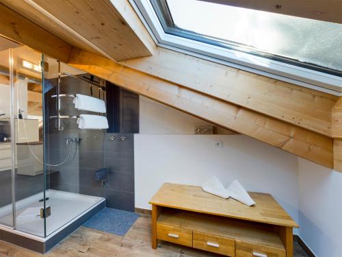 ein Bad im Dachgeschoss mit einer Dusche, einem Waschbecken und einem Fenster in der Unterkunft Herzstück in Garmisch-Partenkirchen