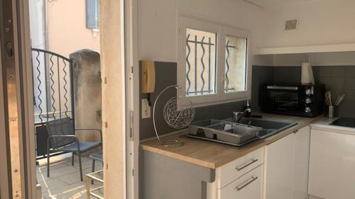 une cuisine avec un évier et un micro-ondes dans l'établissement Logement sur pte cour, rez de chaussée, WIFI, CLIM, à Vedène