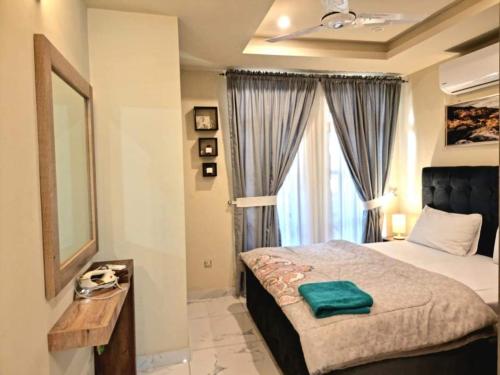 ein Schlafzimmer mit einem Bett und einem großen Fenster in der Unterkunft Tranquil & Delightful 1 Bed Apt In Bahria Town in Rawalpindi