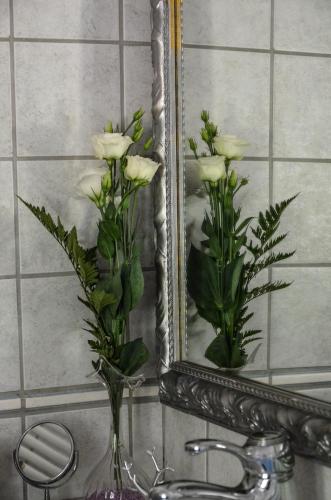 a vase of white flowers in front of a mirror at Valverde Guest House in Tarquinia