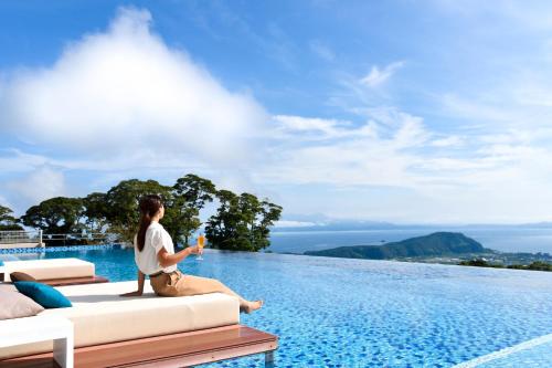 a woman sitting on a couch next to a pool at Bettei Amafuru Oka in Ibusuki