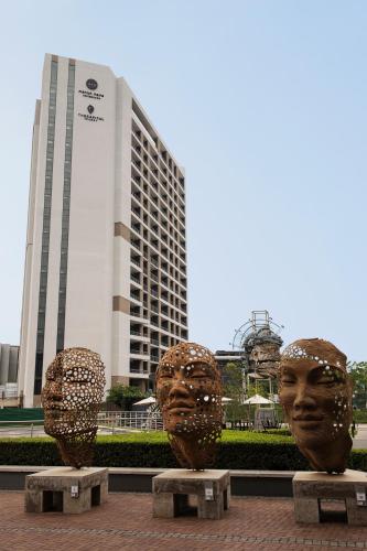 two large bronze headulptures in front of a building at The Capital Trilogy Menlyn Maine in Pretoria