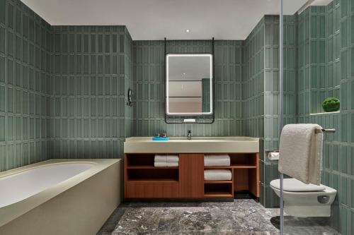 a bathroom with a sink and a tub and a mirror at Artyzen Habitat Qiantan Shanghai in Shanghai