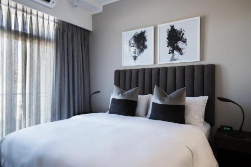 a bedroom with a large bed with white sheets and pillows at The Capital Trilogy Menlyn Maine in Pretoria