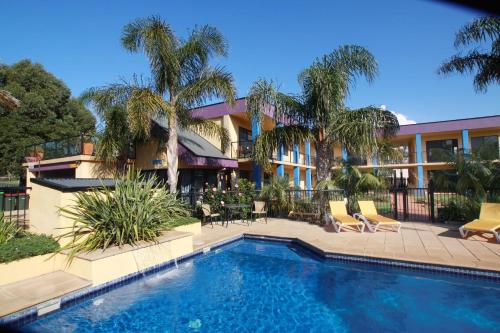 a swimming pool in front of a building with palm trees at Nautilus Apartments Merimbula in Merimbula
