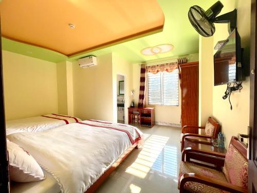 a bedroom with two beds and a flat screen tv at Huy Hoàng Hotel in Dồng Văn