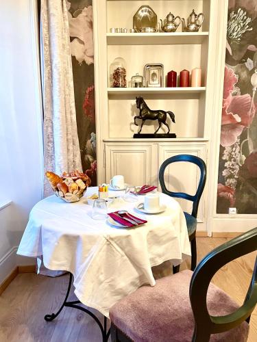 a table with a white table cloth on it with a horse statue at La Maison Gervaiserie & Spa in Réville