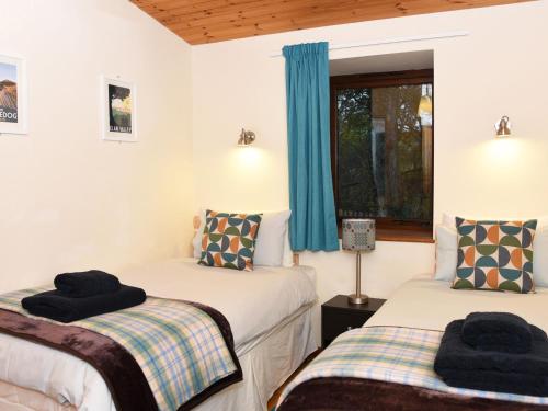 ラアアデルにあるSycamore Lodgeの青いカーテンが備わる客室のベッド2台