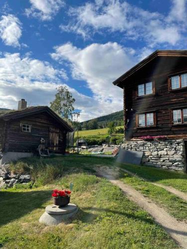 a house with a pot of flowers in front of it at Stallen - koselig lite hus på gårdstun in Skjåk