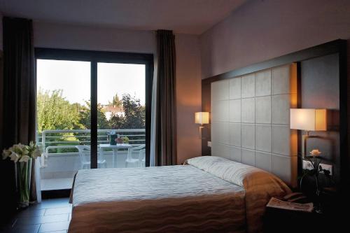 a hotel room with a bed and a large window at Hotel Porto Azzurro in Sirmione
