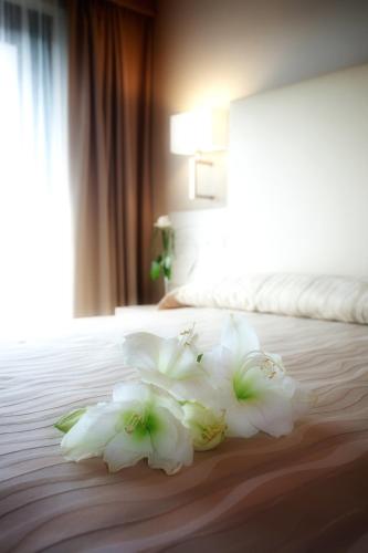 a pile of white flowers on a bed at Hotel Porto Azzurro in Sirmione