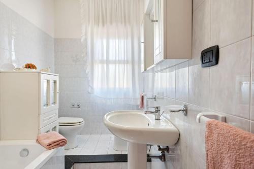 La salle de bains blanche est pourvue d'un lavabo et de toilettes. dans l'établissement Appartamento Sicilia Etna e Mare, à Mascali