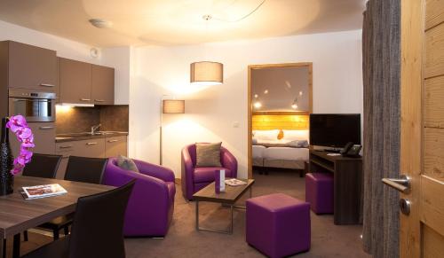 a living room with purple furniture and a bedroom at Résidence Le Chalet du Mont Vallon in Les Menuires