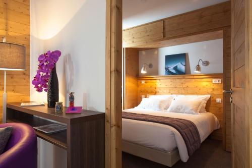 een slaapkamer met een groot bed met een houten hoofdeinde bij Résidence Le Chalet du Mont Vallon in Les Menuires