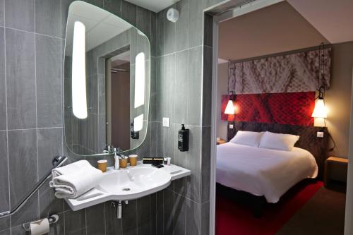 a bathroom with a sink and a bed and a mirror at ibis Moulins in Moulins