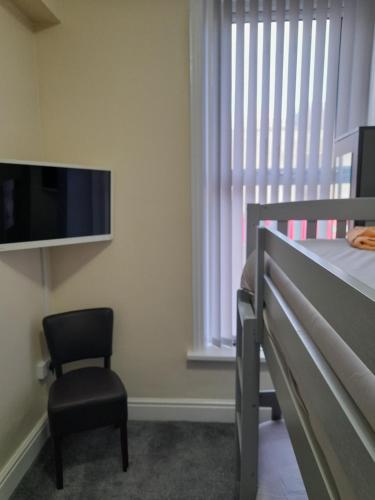 a bedroom with a bed and a chair and a tv at NIRO's Hotel in Blackpool