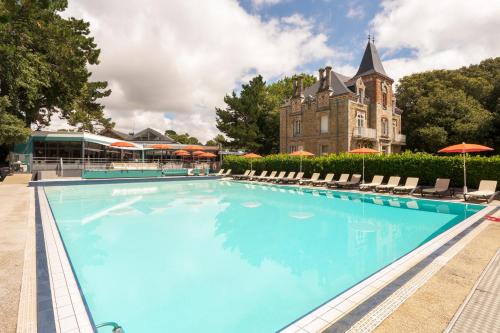 une grande piscine avec des chaises et un bâtiment dans l'établissement Hotel Ker Juliette, à Pornichet