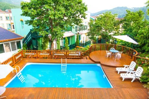 einen Pool auf einer Terrasse mit Stühlen und einem Tisch in der Unterkunft Bellus-Rose Pension Gyeongju in Gyeongju