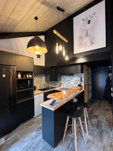 une cuisine avec des armoires noires et un comptoir avec une table dans l'établissement chalet de l ours, à Bolquère-Pyrénées 2000