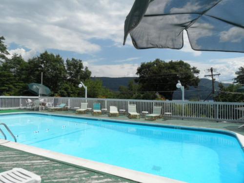 a large swimming pool with chairs and a fence at Pinebrook Motel in Lake George