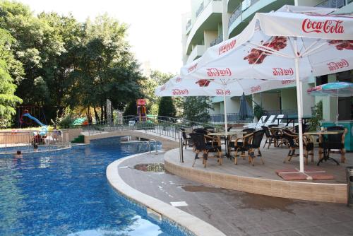 a pool with tables and umbrellas next to a hotel at Hotel Perunika in Golden Sands