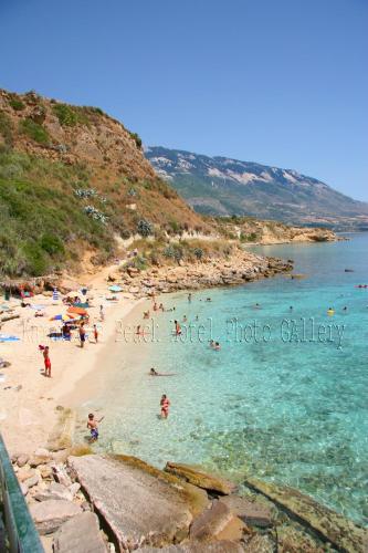 a beach with a bunch of people in the water at Karavados Beach Hotel in Karavadhos