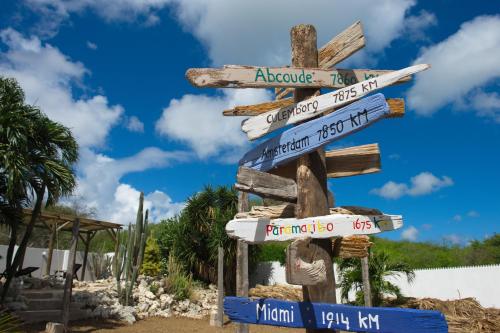 a street sign with arrows in different languages at Bantopa Apartments in Willemstad