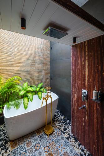 a bathroom with a tub with a plant in it at SaffronStays Turquoise Maison - 3BR pool villa with jacuzzi, bonfire & fruit garden near Lake Kalote, Karjat in Karjat