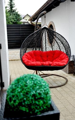 a swing with a red cushion on a patio at Pensiunea Ellemar in Vatra Dornei
