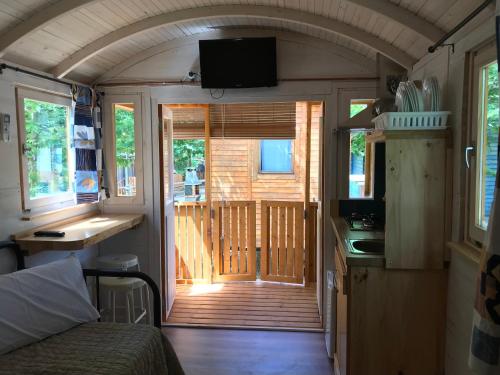 une porte ouverte menant à une terrasse couverte dans une petite maison dans l'établissement Càmping l'Alguer, à Les Planes d'Hostoles