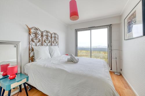 une chambre avec un grand lit blanc avec une grande fenêtre dans l'établissement Panoramic view of Paris, à Paris