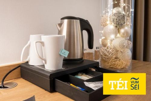 a tea kettle and cups sitting on a shelf at City Hotel in Luxembourg