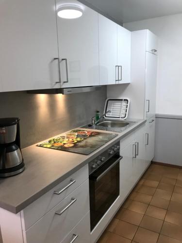 a kitchen with white cabinets and a stove top oven at Ferienanlage Achtern Diek in Thalingburen