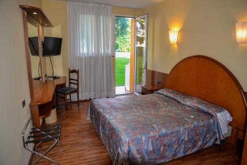 1 dormitorio con 1 cama, TV y ventana en Hotel Continental, en Garda