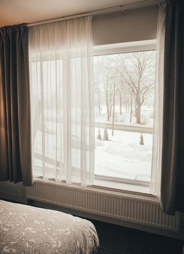 a bedroom window with a view of a snow covered yard at Ring Stop Holiday Apartment in Sigulda