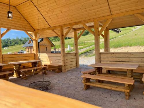 a wooden pavilion with wooden tables and benches at RESET INN in Zawóz