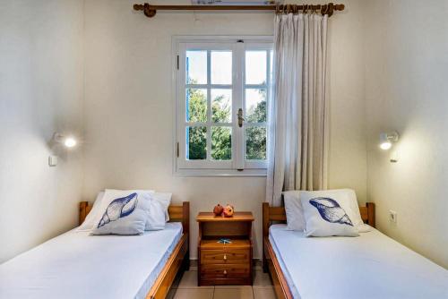 two twin beds in a room with a window at Blue Beach House in Kissamos