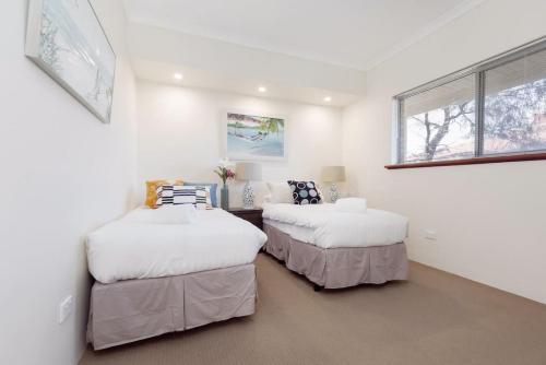 Dos camas en una habitación con paredes blancas y una ventana. en A4 - Deluxe 1 bedroom, 1 bathroom apartment, en Perth