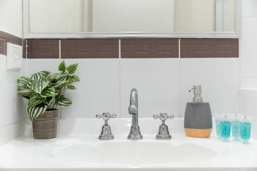 un lavabo con 2 grifos y una planta en A4 - Deluxe 1 bedroom, 1 bathroom apartment, en Perth