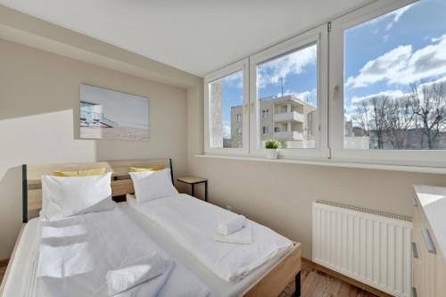 a bedroom with two beds and two windows at Comfort Apartments Gdynia Centrum in Gdynia